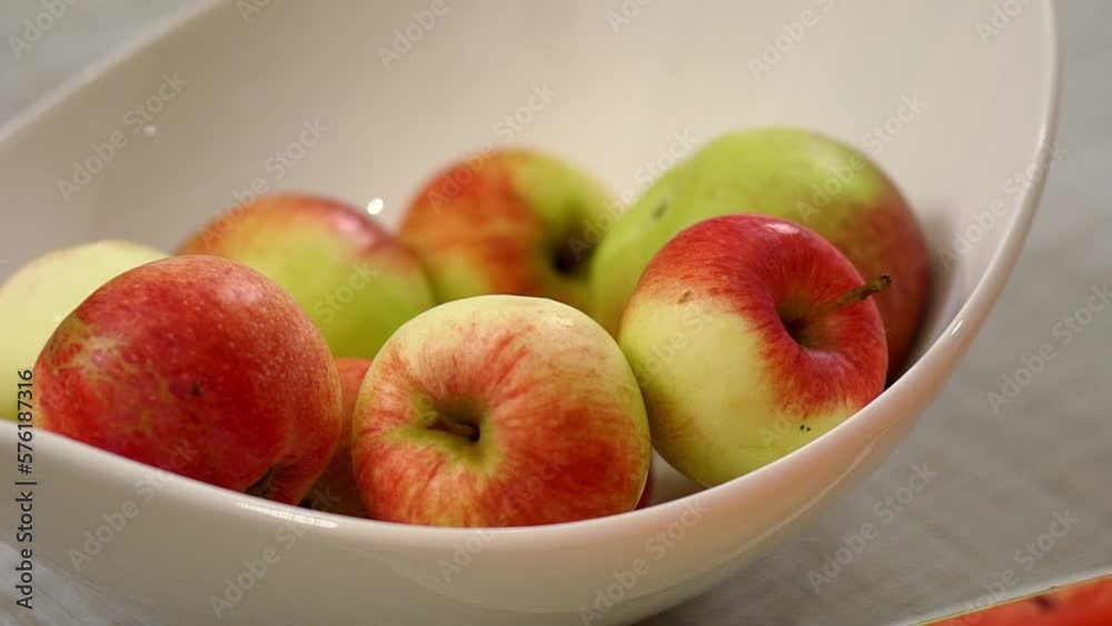 Fresh apples lie in white ceramic bowl on kitchen table Fresh apples lie in white ceramic bowl on kitchen table