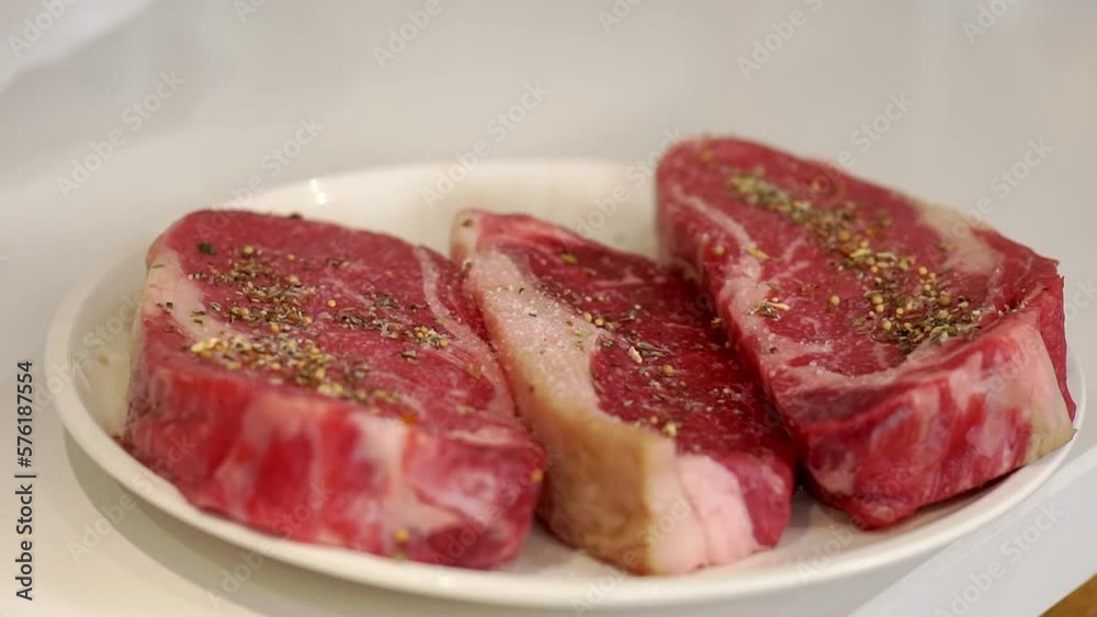 Large pieces of raw veal steak with fragrant spices on plate Large pieces of raw veal steak with fragrant spices on plate