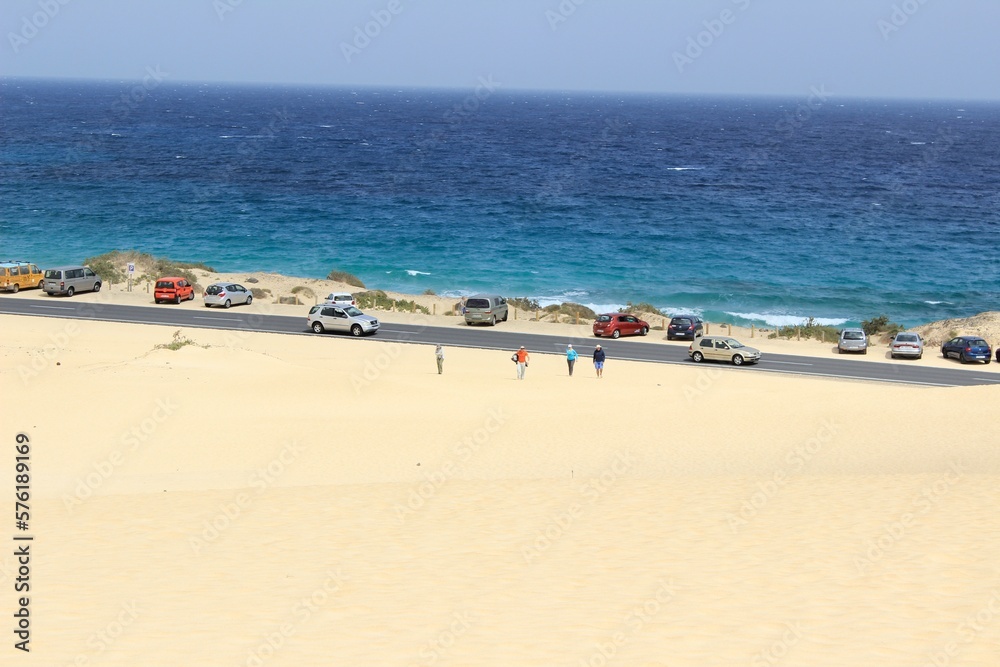 A spectacular paved road that passes through the desert and sand dunes of Corralejo in Fuerteventura. Contrast between ocean and desert territory.