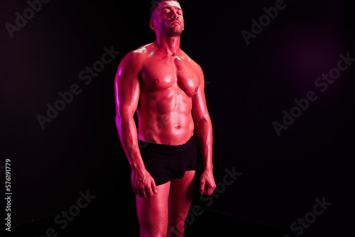Man professional athletes with naked torso in athletic uniforms, isolated on a multicolored background in neon light. Advertising, sports, active lifestyle, competition, challenge concept