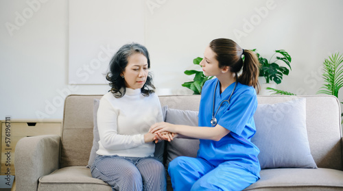 Medical doctor holing senior patient's hands and comforting her at home