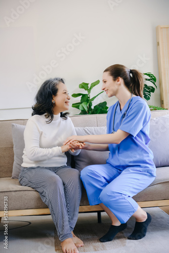 Medical doctor holing senior patient's hands and comforting her at home