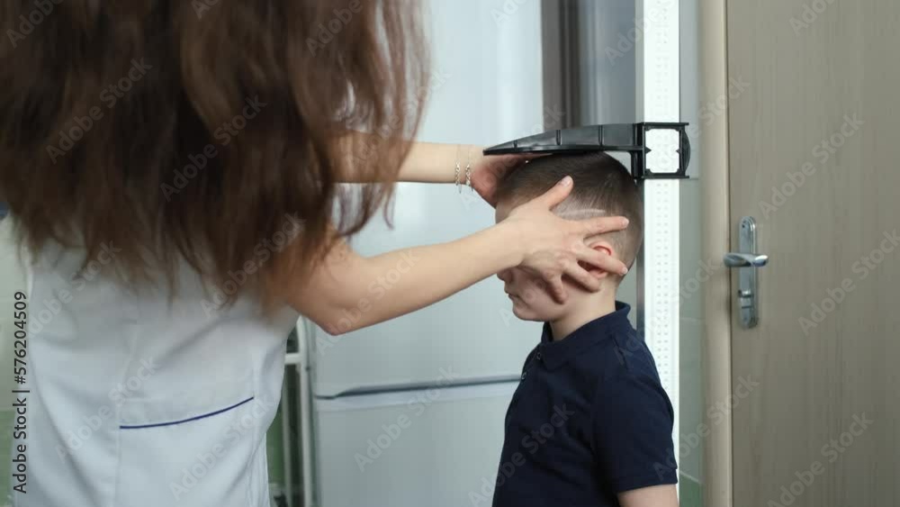 the boy is measured height in the doctor's office the boy is measured height in the doctor's office