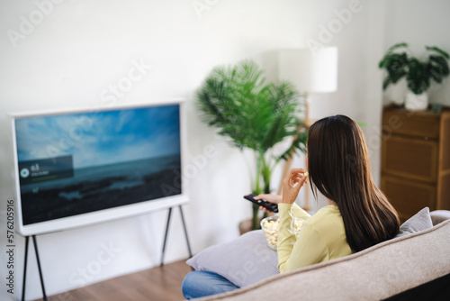 Asian woman Watching smart TV and using remote controller Hand holding television audio remote control at home with the remote control television