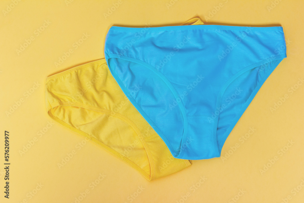 yellow and blue women's panties made of cotton on a yellow background close-up top view
