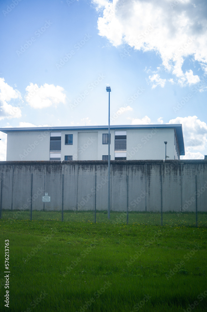 A prison, with gray high walls and barbed wire concrete walls and dreary 