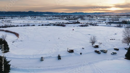 Boseman Montana Aerial Winter sunset over snowy suburban park, orbit right with 4k drone over ice fishermen with mountain backdrop photo