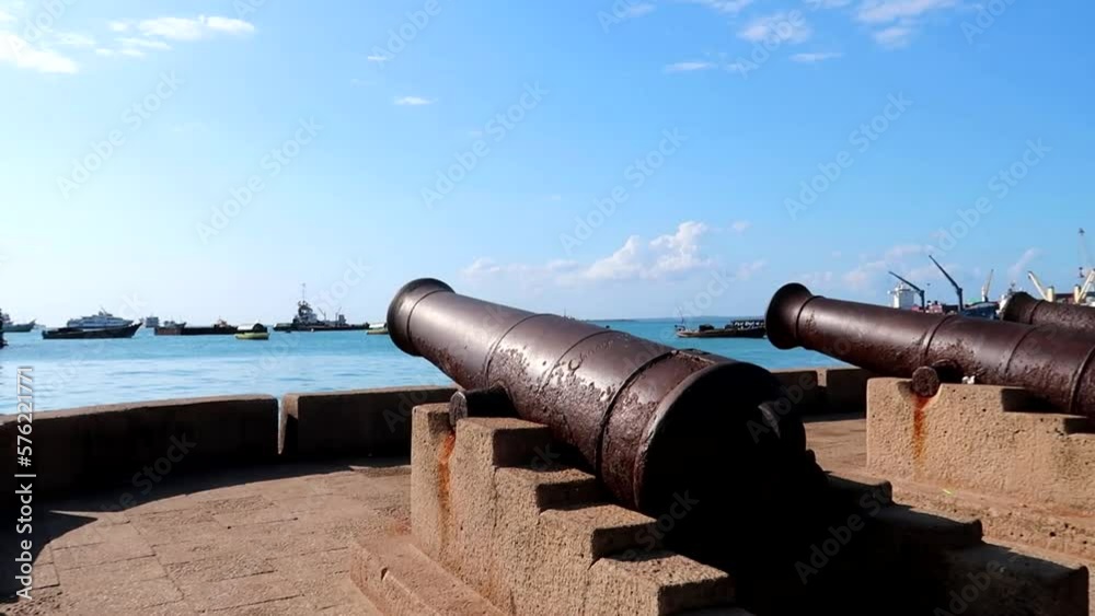 Panning shot of old rusted cannons with boats navigating in the port of Forodhani. Stone Town, Zanzibar Panning shot of old rusted cannons with boats navigating in the port of Forodhani. Stone Town, Zanzibar