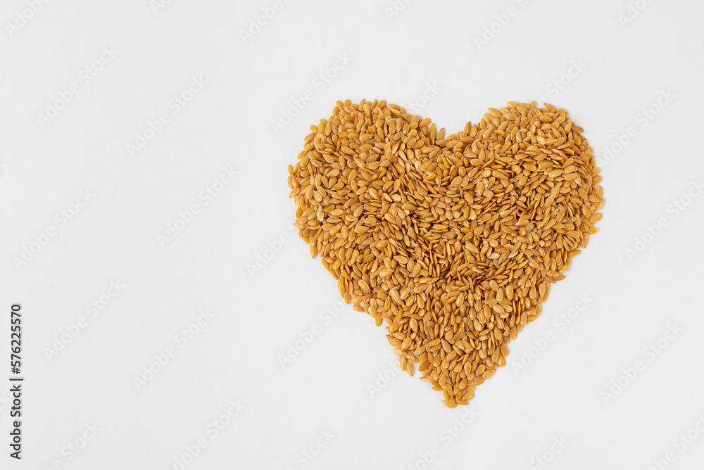 Heart shape layer of mix golden and brown flax seeds isolated on white background whith copy space. Heart shape layer of mix golden and brown flax seeds isolated on white background whith copy space.