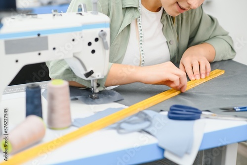 Portrait of a beautiful seamstress carrying a tape measure and working in a textile factory