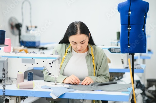 Portrait of a beautiful seamstress carrying a tape measure and working in a textile factory