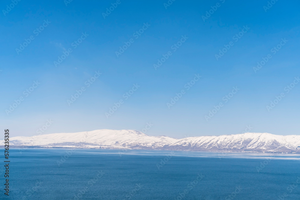 Aerial panorama view snow covered mountains. Snowy mountain ridge on winter sunrise. Stunning mountains range covered with snow over beautiful lake