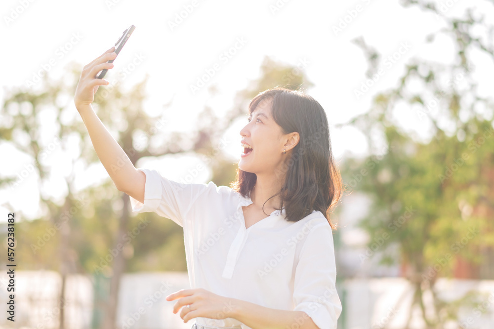 Portrait beautiful young asian woman with smart mobile phone around outdoor nature view in a sunny summer day Portrait beautiful young asian woman with smart mobile phone around outdoor nature view in a sunny summer day