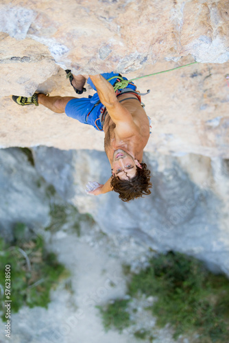 Man looking up during rock climbing, Pobla de Segur, Lleida, Spain photo