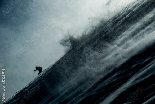 Skier skiing through snow drift and dark cloudy skies in Ski Resort photo