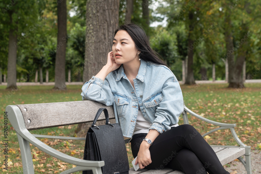 Asian traveller enjoying a rest on a bench in a park Asian traveller enjoying a rest on a bench in a park