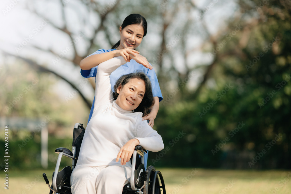 Asian careful caregiver or nurse and the happy patient in a wheelchair are walking in the garden to help and encourage and rest your mind with green nature. Asian careful caregiver or nurse and the happy patient in a wheelchair are walking in the garden to help and encourage and rest your mind with green nature.