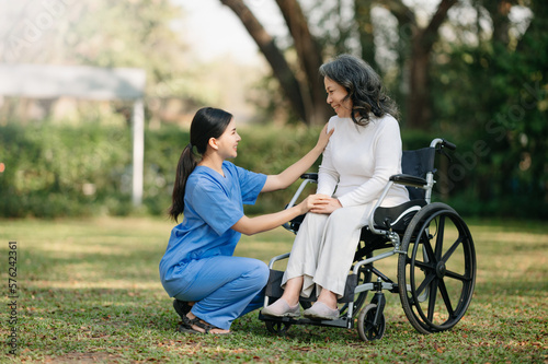 Elderly asian senior woman on wheelchair with Asian careful caregiver. Nursing home hospital garden concept. in sun light