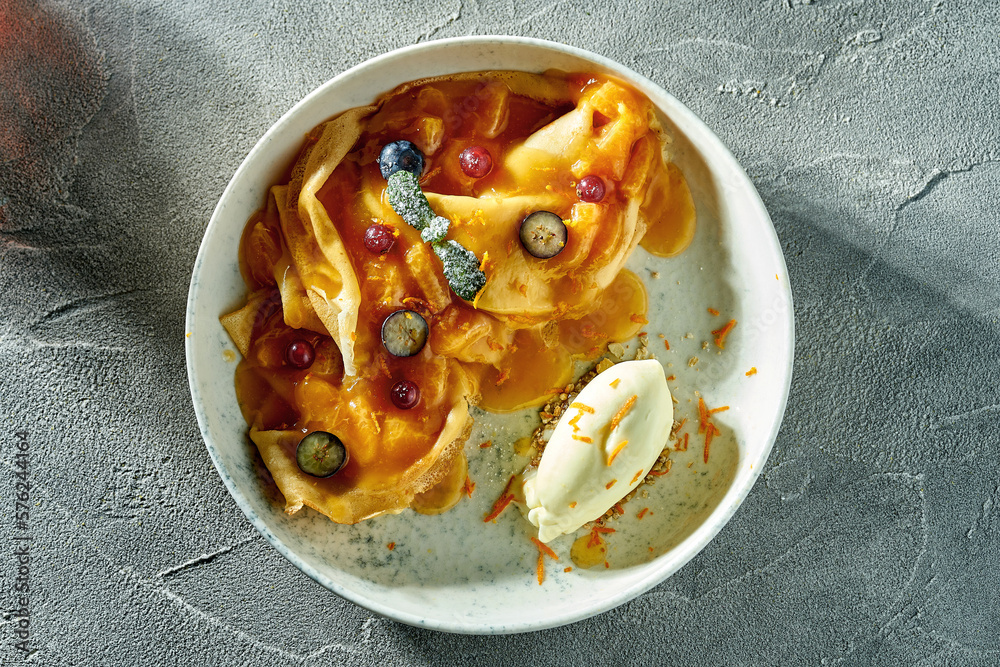 Classic crepe suzette with orange jam, ice cream and berries in a plate. A delicious dessert