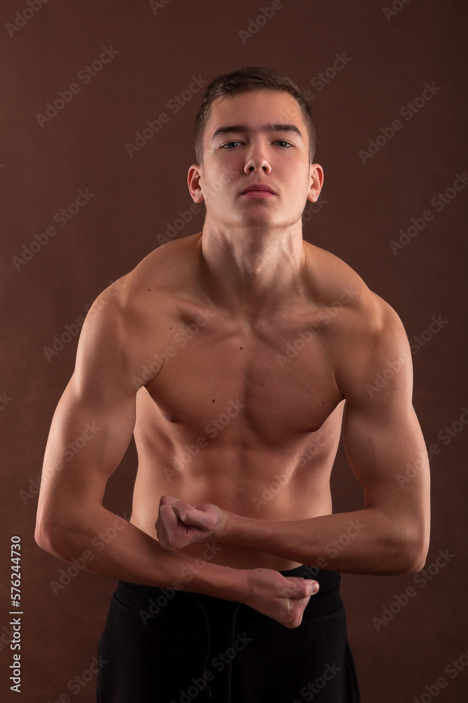 Fototapeta premium Handsome muscular shirtless adolescent boy flexing muscles.