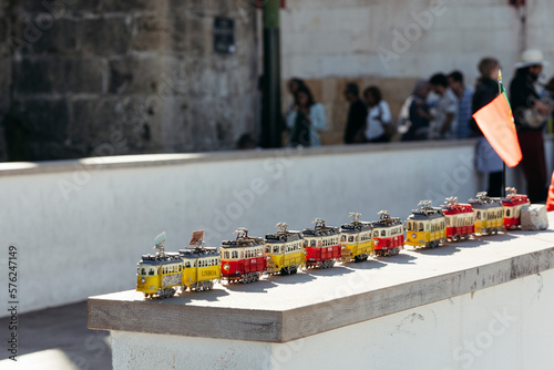 Typical gifts in form of trams on tourist street in Lisbon Portugal against background of blurred walking people on sunny day.