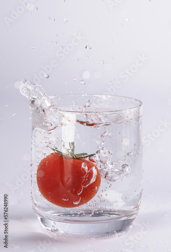 Tomate fällt in Wasserglas