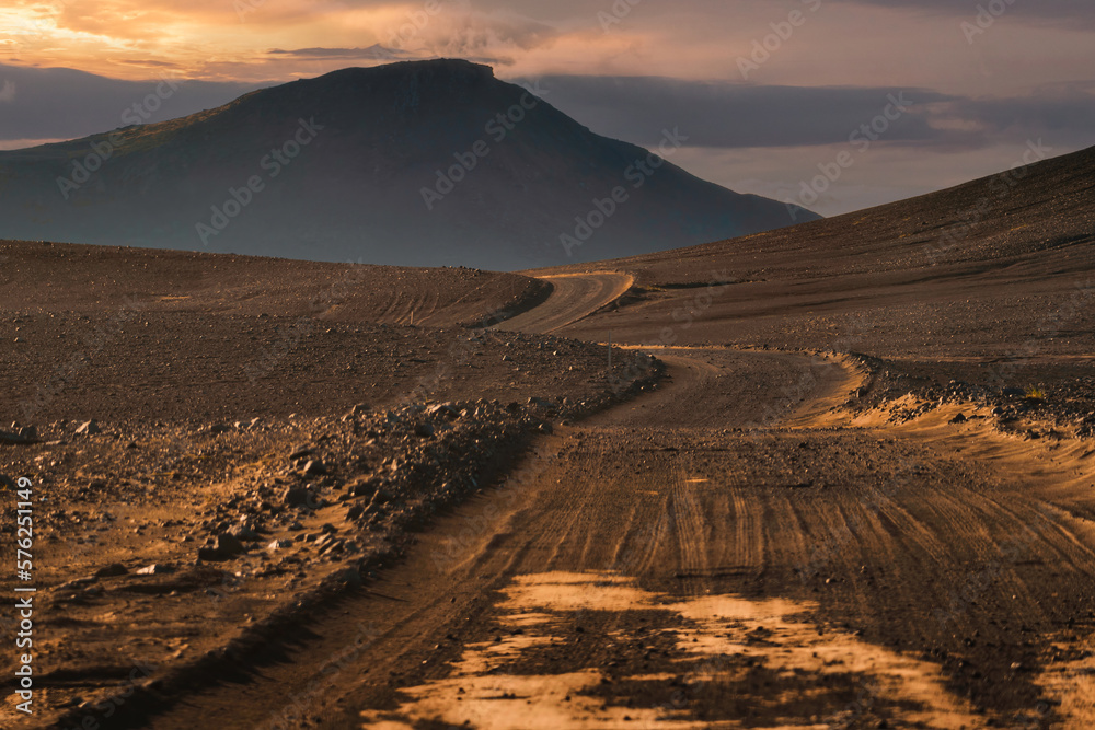 Fototapeta premium Dirt road and volcanic mountain to Landmannalaugar among remote wilderness in the evening at Icelandic Highlands