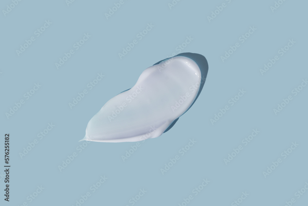 White smear of cosmetic cream on a blue background. Creamy foundation texture isolated. Smear of face cream. Close up of cream texture. White smear of cosmetic cream on a blue background. Creamy foundation texture isolated. Smear of face cream. Close up of cream texture.