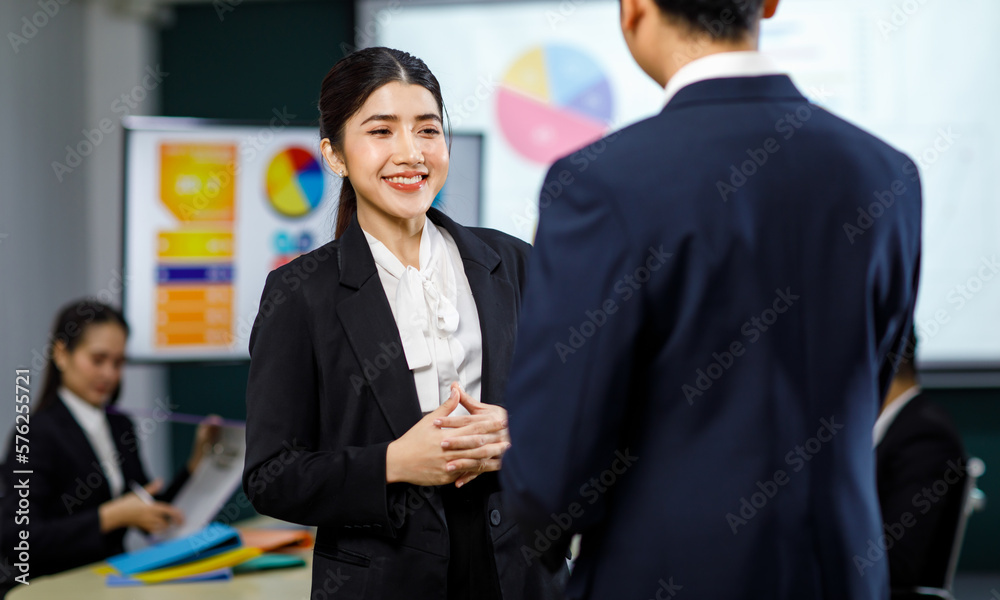 Millennial Asian professional successful male businessman manager female businesswoman employee in formal business suit standing discussing brainstorming working together in meeting room