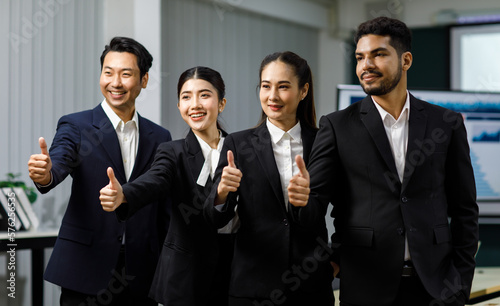 Millennial Asian Indian professional successful male businessmen female businesswomen management group in formal business suit stand side by side smiling celebrating holding thumbs up posing together