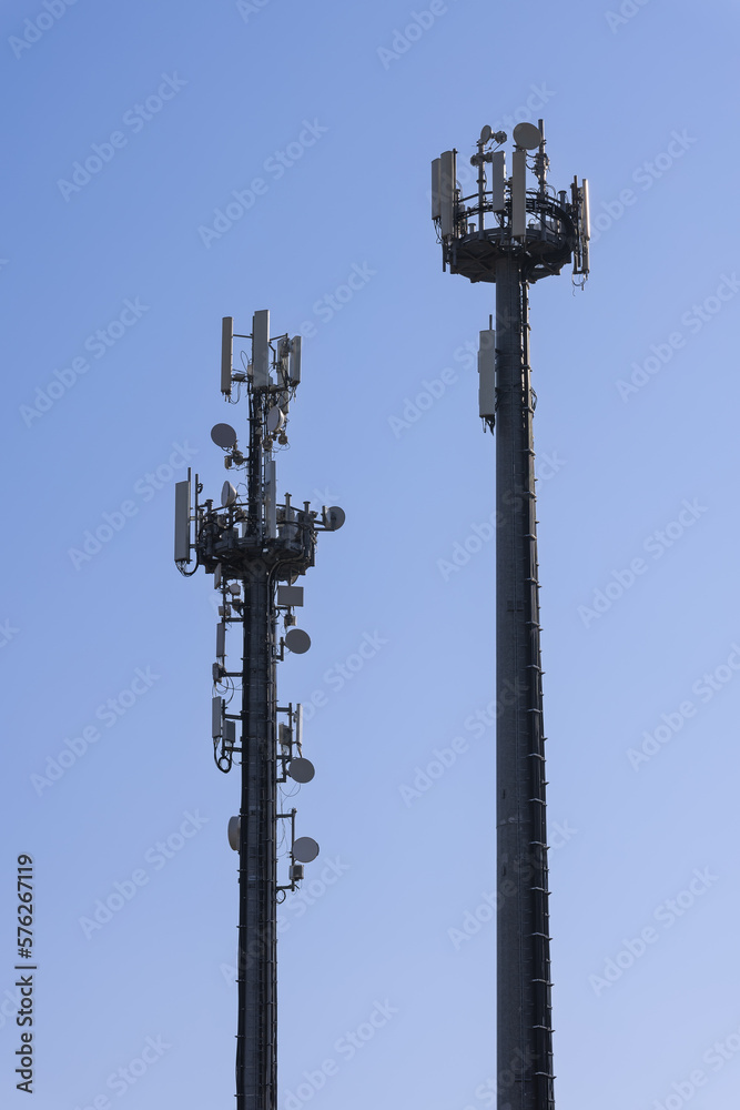 Telecommunications tower with cellular antennas and repeaters against a clear blue sky (Vertical photos)