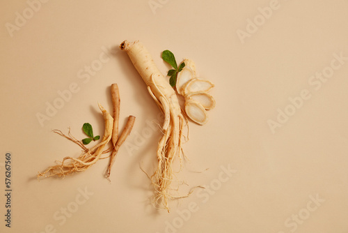 Korean ginseng root and some ginseng slices decorated on beige background. Blank space for text or product adding photo