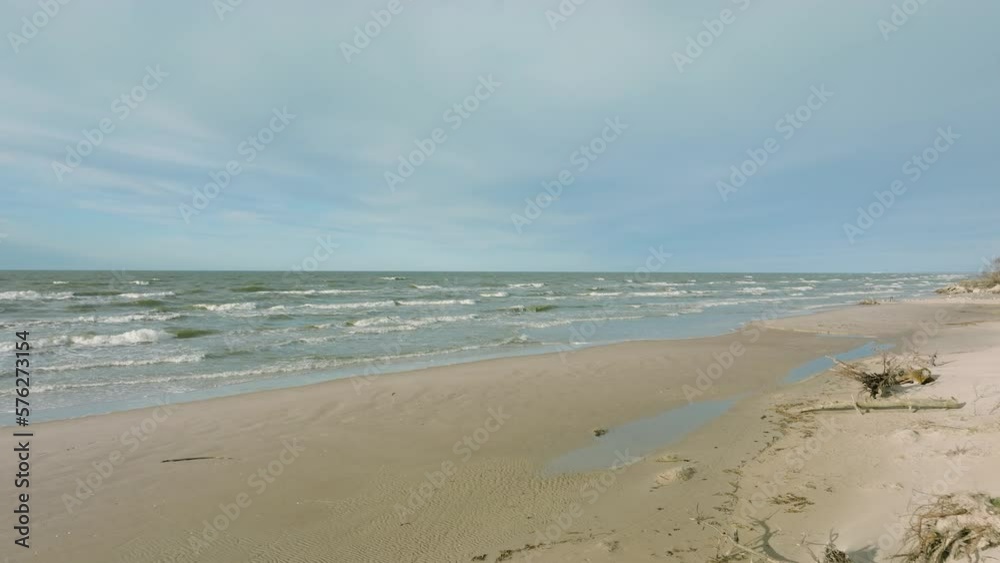 Aerial establishing view of Baltic sea coast, sunny day, white sand seashore dunes damaged by waves, pine tree forest, coastal erosion, climate changes, wide angle drone shot moving backward low Aerial establishing view of Baltic sea coast, sunny day, white sand seashore dunes damaged by waves, pine tree forest, coastal erosion, climate changes, wide angle drone shot moving backward low