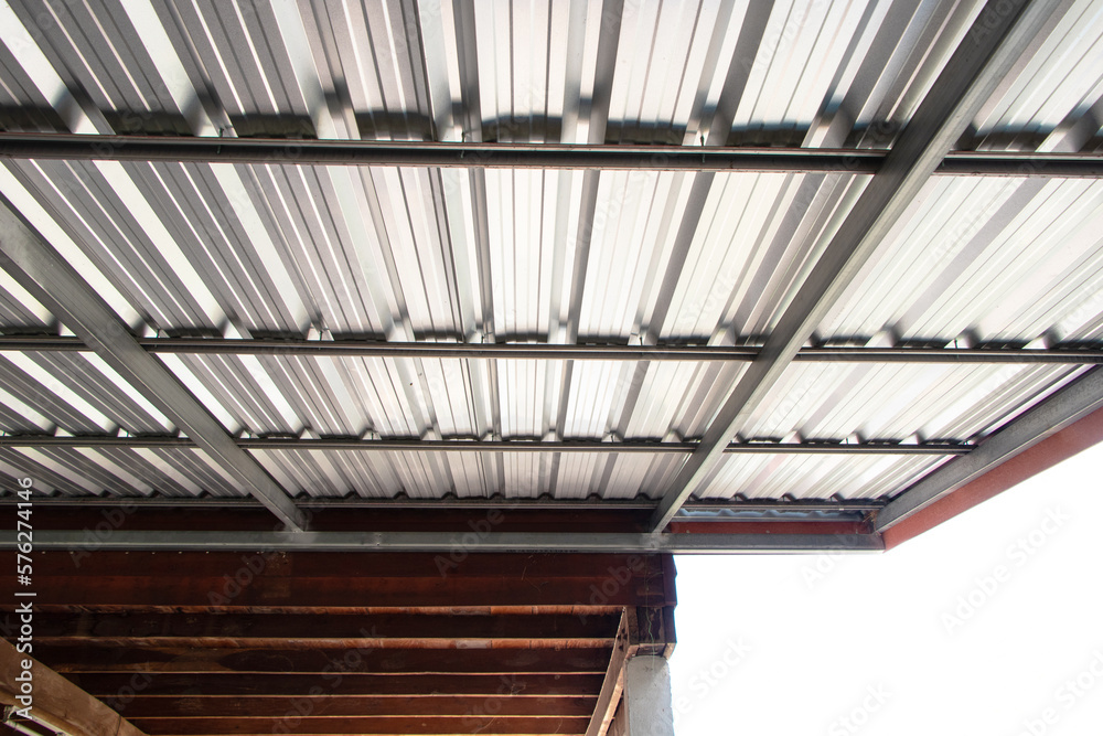 Obraz premium Roof silver steel strong metal structure large made with plate aluminum. Bolts attached to each other, durable from strong winds. Strong garage sunlight shines. Attached to side of wooden house.