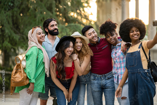 Multiethnic guys and girls taking selfie outdoors with backlight - Happy lifestyle friendship concept about young multicultural people having fun together in the city © PintoArt