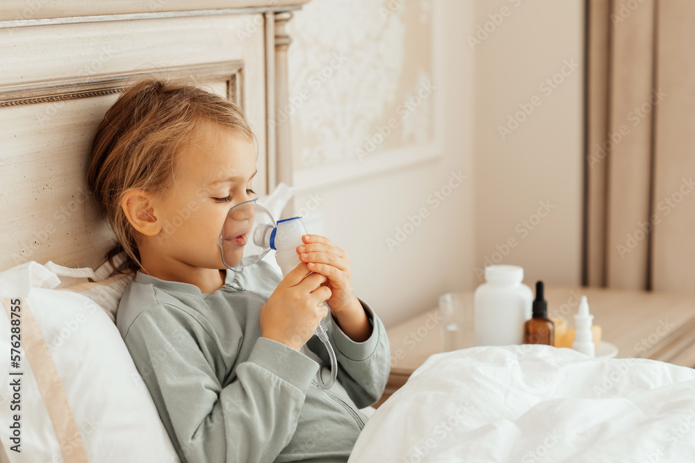 Fototapeta Little girl kid making inhalation with nebulizer at home at