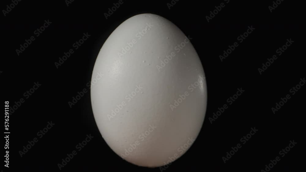 A white chicken egg rotates on a black background. Isolate close-up.