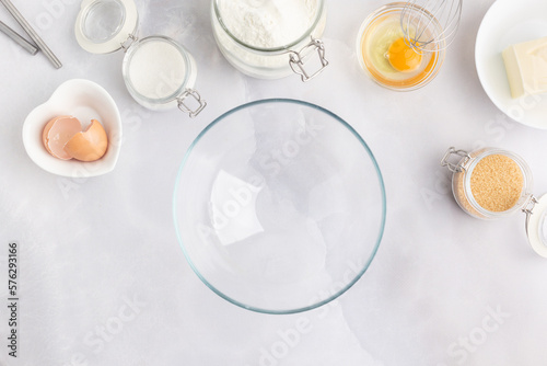Various baking ingredients - flour, eggs, sugar, butter and kitchen utensils on grey background. Top view.