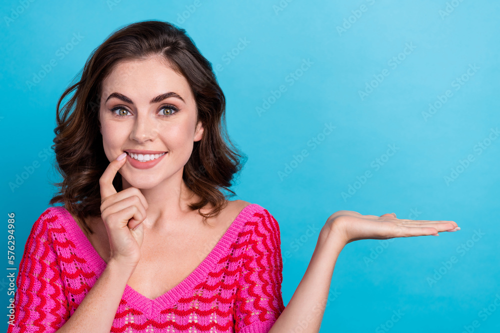 Photo of brown curly hair excited cute lady bite nail satisfied smile wish black friday brand collection hold palm isolated on blue color background Photo of brown curly hair excited cute lady bite nail satisfied smile wish black friday brand collection hold palm isolated on blue color background