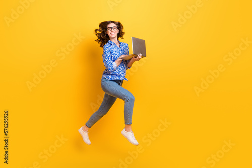 Full body profile photo of cheerful active lady jumping rush use wireless netbook isolated on yellow color background