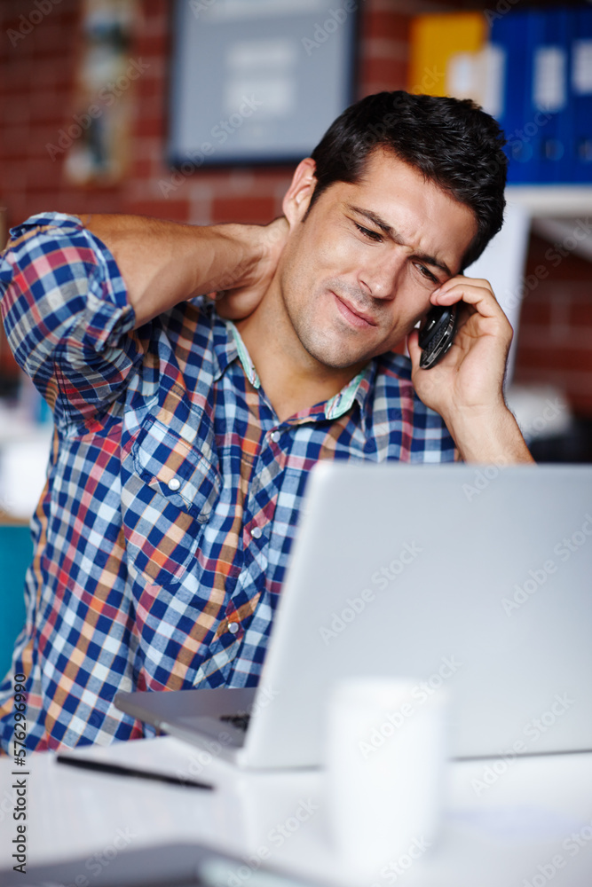 Work is getting to him. A stressed young entrepreneur rubbing his neck while on the phone to a client. Work is getting to him. A stressed young entrepreneur rubbing his neck while on the phone to a client.