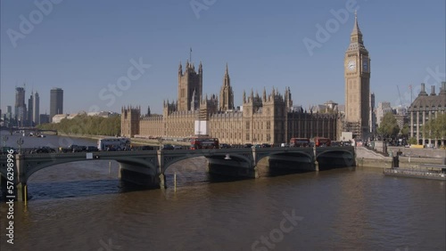 Aerial drone shot flying towards Westminster Bridge, Westminster Abbey and Big Ben over the River Thames with London Buses and traffic crossing Westminster Bridge on a bright clear sunny day.