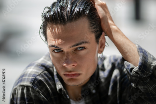 Portrait of modern confident guy posing on sunny city street