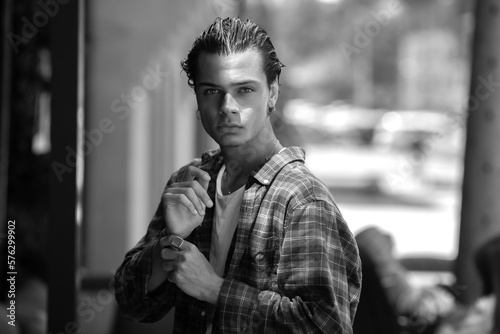 Black and white portrait of guy walking along summer city street