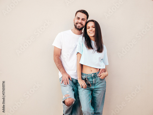 Smiling beautiful woman and her handsome boyfriend. Woman in casual summer jeans clothes. Happy cheerful family. Female having fun. Sexy couple posing in the street near wall