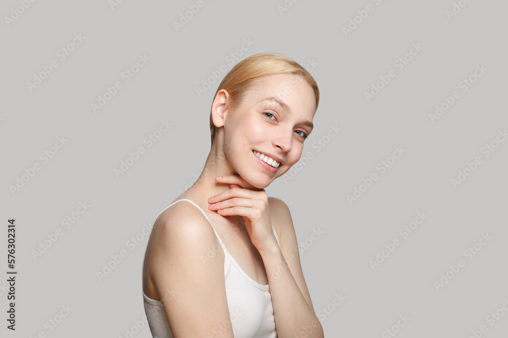 Happy blonde woman with ponytail smiling isolated on light grey background. Beauty, cosmetics, skincare Happy blonde woman with ponytail smiling isolated on light grey background. Beauty, cosmetics, skincare
