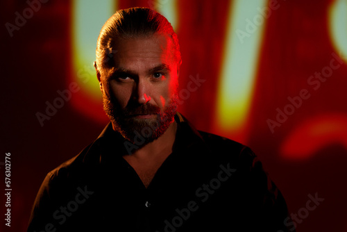 Confident bearded man on dark background with neon lights