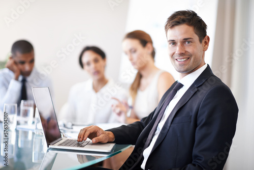 Hes always connected and available. Portrait of a happy businessman using a laptop during a meeting.