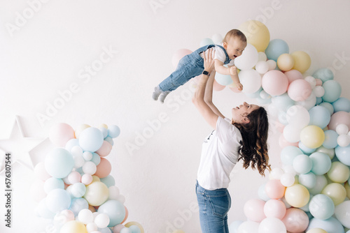 Wall Mural Mother plays with her son celebrating first birthday of baby boy among colorful balloons