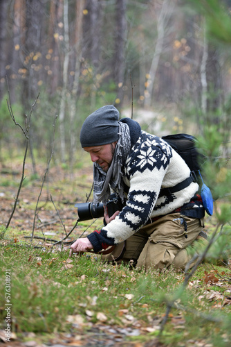 male photographer, forest flowers. young man photographing the beauty of nature. man in the forest. spring or autumn season, natural background. Outdoors and nature. SLR camera. macro photographer © Oleksandr Filatov